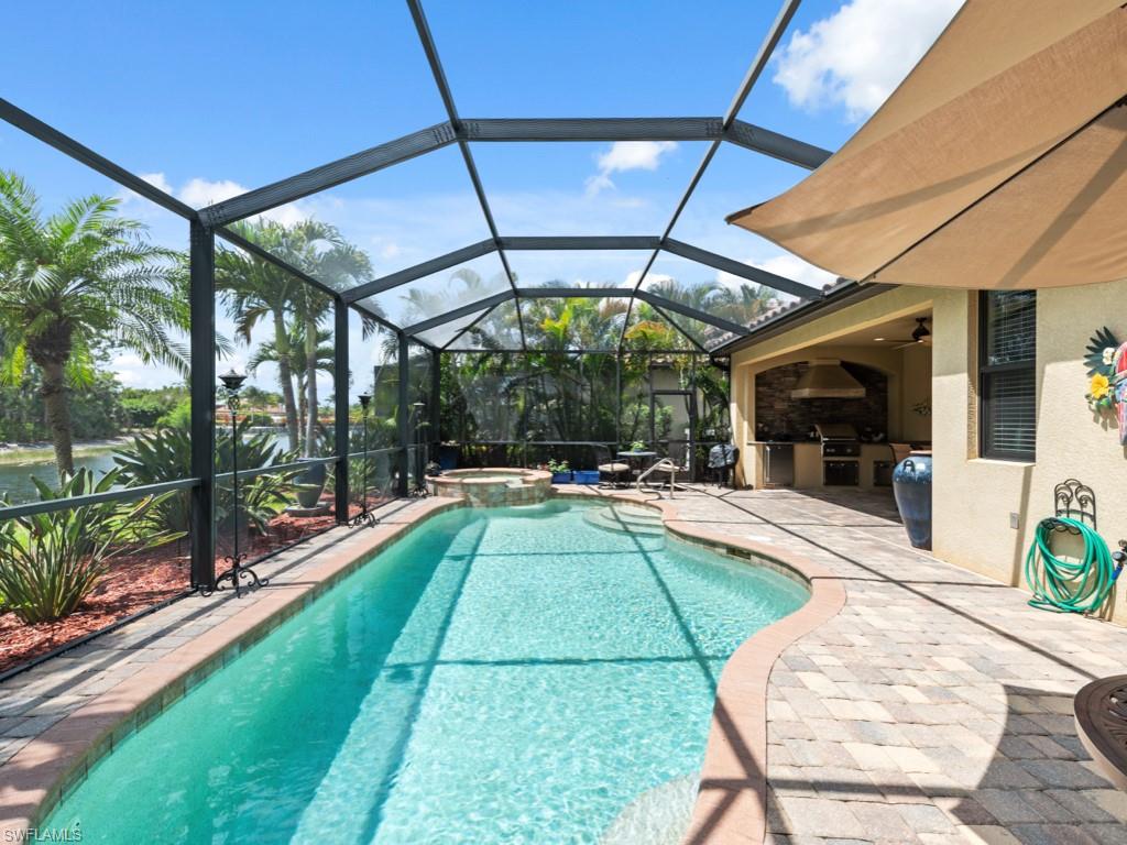 View of swimming pool with a patio, a lanai, a pool with connected hot tub, and an outdoor kitchen