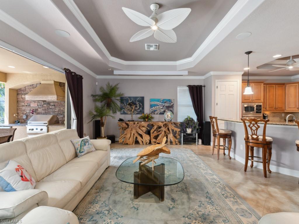 9522 Piacere Way Naples, FL 34113 - Photo 15 of 48 Living area with visible vents, ornamental molding, a raised ceiling, and ceiling fan