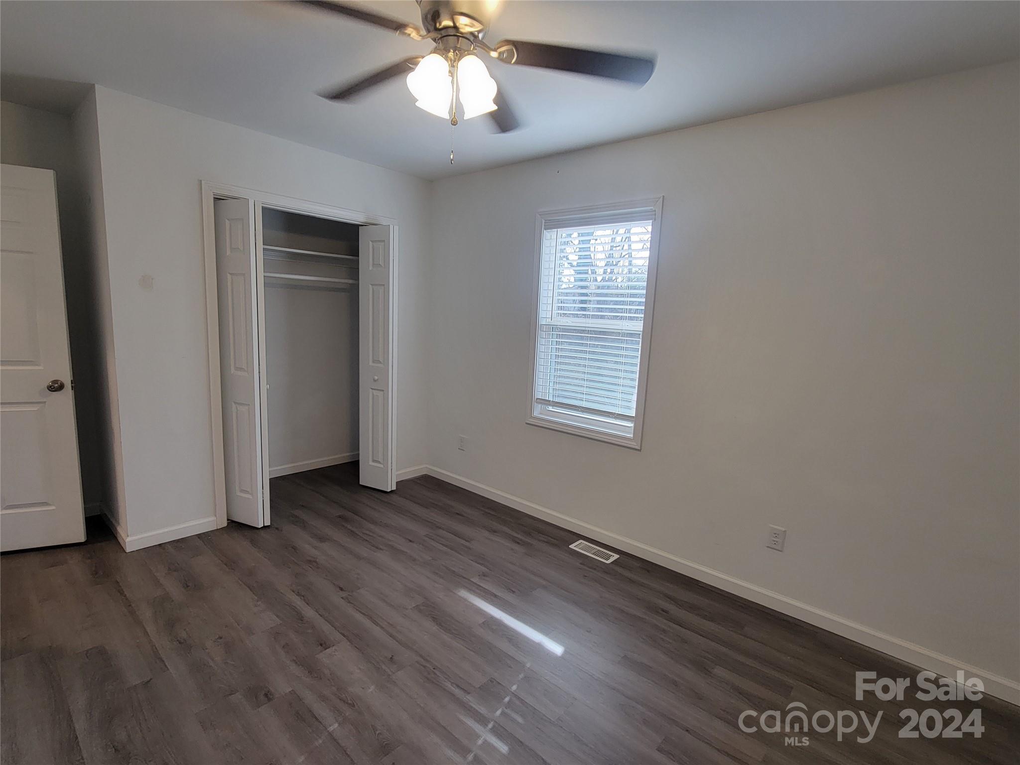 636 Hawthorne Street Hudson, NC 28638 - Photo 17 of 21 an empty room with wooden floor chandelier fan and windows