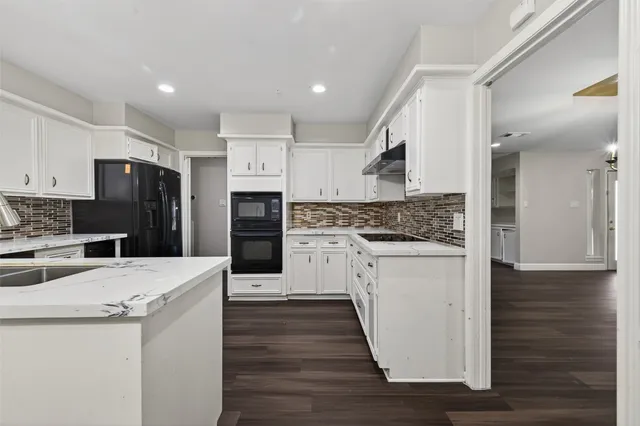 a kitchen with stainless steel appliances kitchen island wooden floors granite counter tops and white cabinets