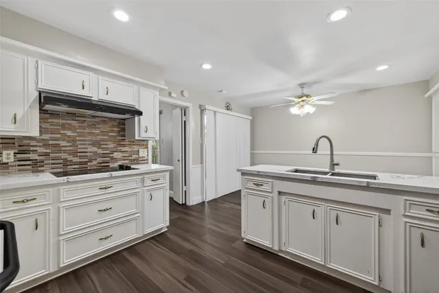 a kitchen with white cabinets and sink