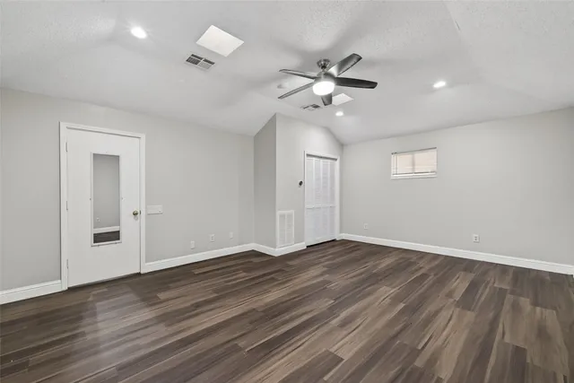 a view of an empty room with wooden floor and a ceiling fan