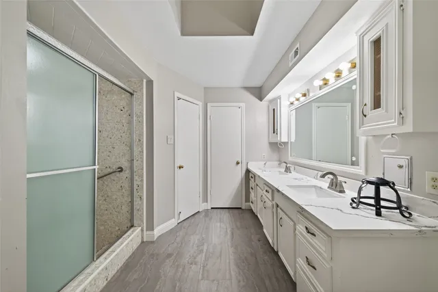 a bathroom with a double vanity sink a mirror and a shower