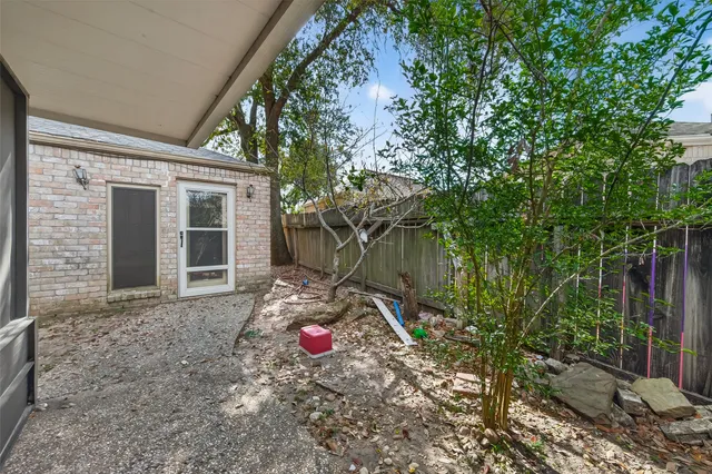 a backyard of a house with table and chairs and wooden fence