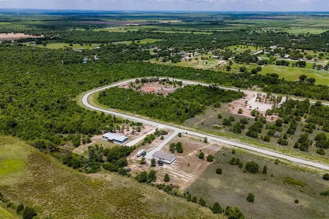 an aerial view of residential houses with outdoor space and trees