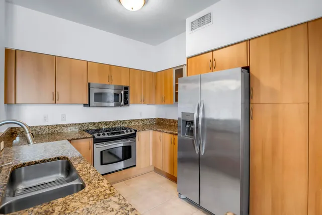 a kitchen with stainless steel appliances granite countertop a refrigerator a stove and a sink with wooden floor