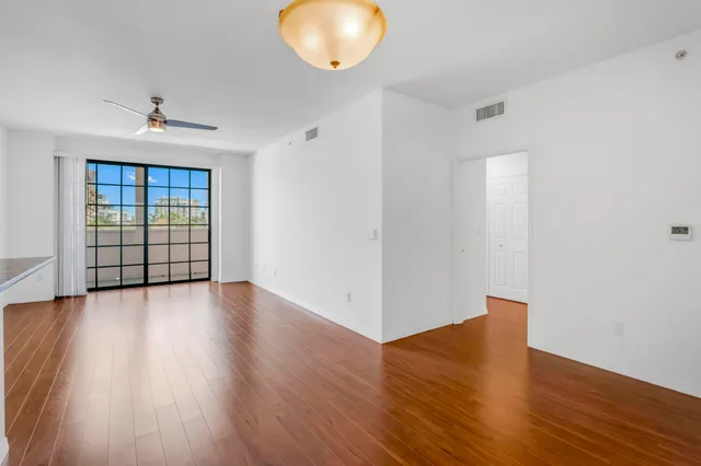 an empty room with wooden floor and windows