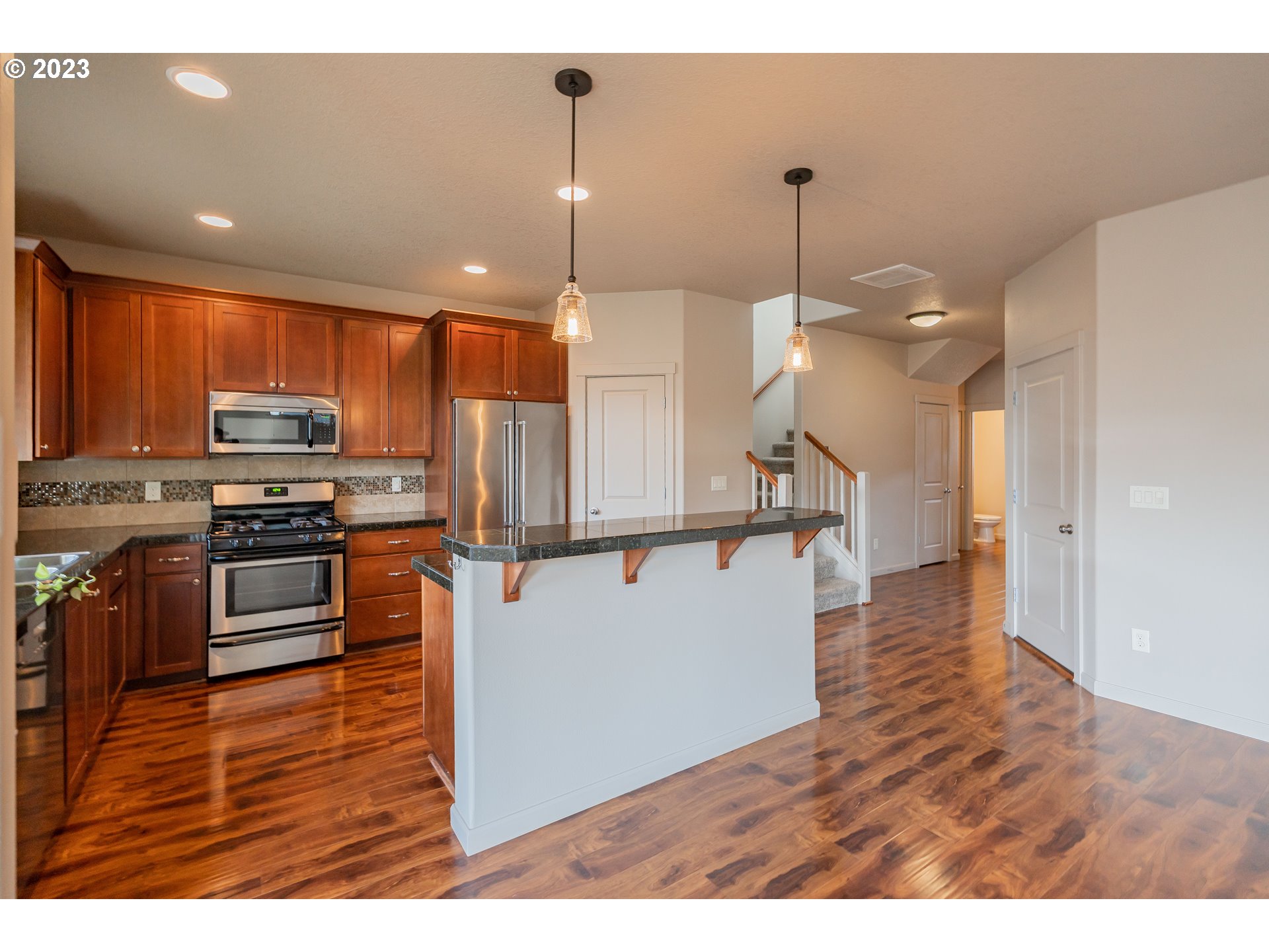 522 North 40th Avenue Ridgefield, WA 98642 - Photo 5 of 32 a kitchen with stainless steel appliances kitchen island granite countertop a refrigerator a stove a microwave oven a sink with island and chairs