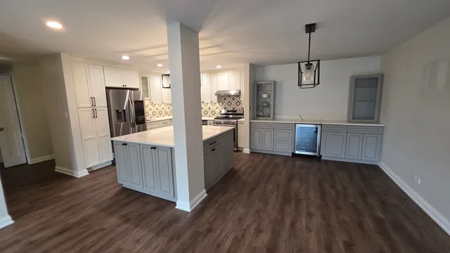 a kitchen with stainless steel appliances granite countertop a refrigerator a sink and wooden floor