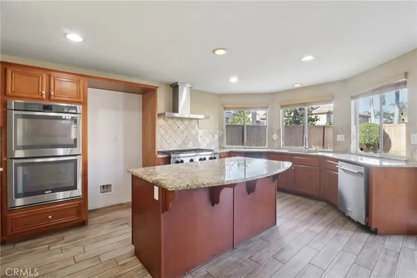 a kitchen with stainless steel appliances granite countertop a sink a stove and a refrigerator