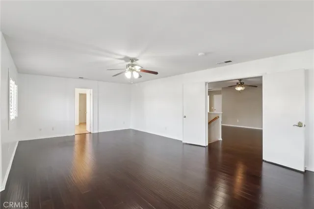 an empty room with wooden floor and chandelier fan