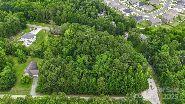 an aerial view of residential house with outdoor space and trees all around