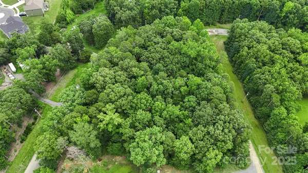 an aerial view of residential house with outdoor space and trees all around