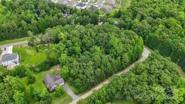 an aerial view of residential house with outdoor space and trees all around