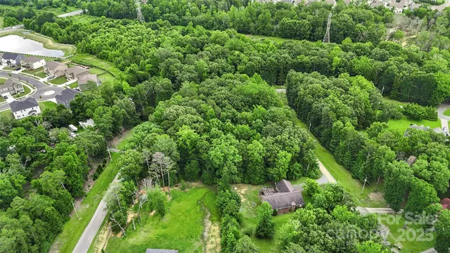 an aerial view of residential house with outdoor space and trees all around