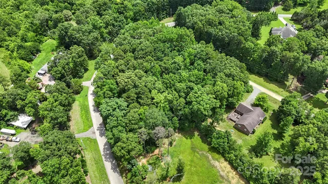 an aerial view of residential house with outdoor space and trees all around