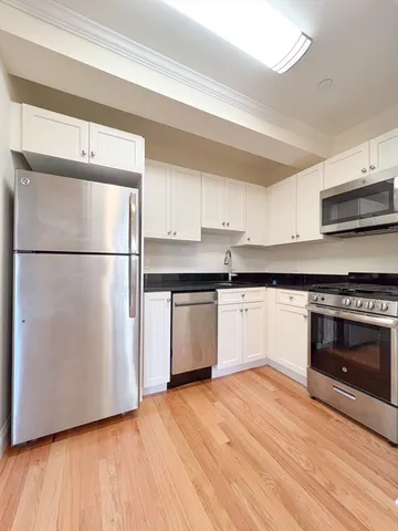 a kitchen with granite countertop a refrigerator and a stove top oven