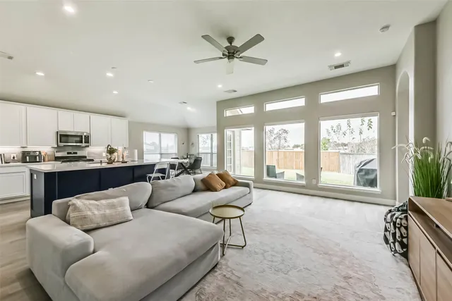 a living room with furniture and a large window with kitchen view