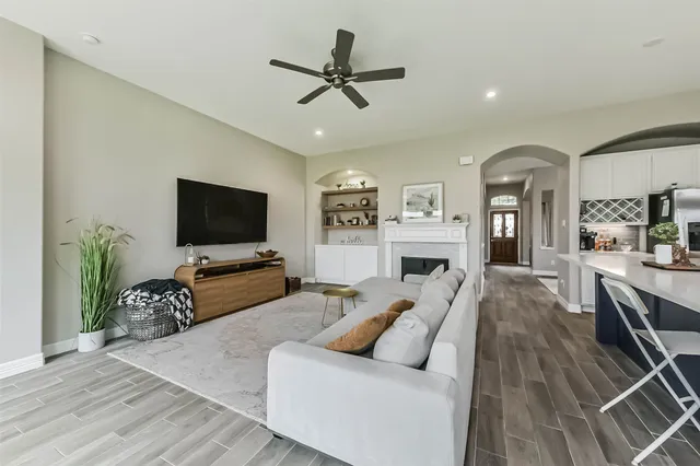 a living room with furniture a ceiling fan and a flat screen tv