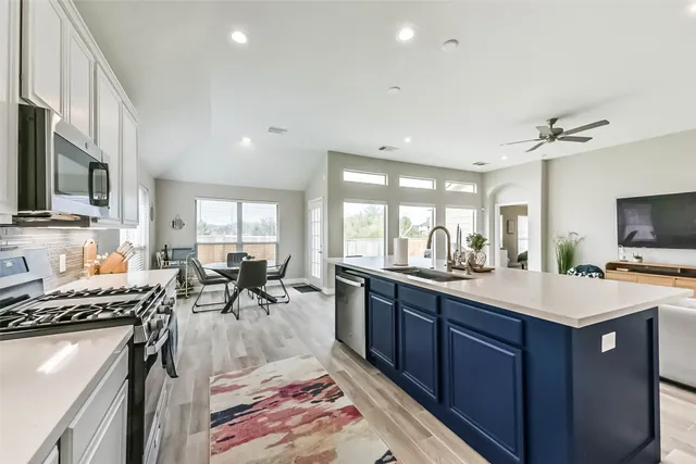 a large kitchen with lots of counter space a sink appliances and cabinets