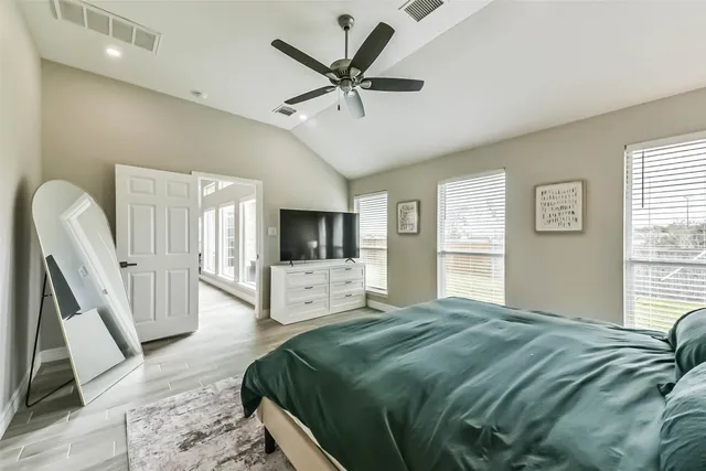 a spacious bedroom with a large bed a flat screen tv and a large window