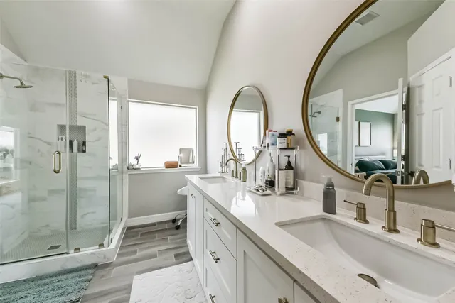 a bathroom with a double vanity sink mirror and shower