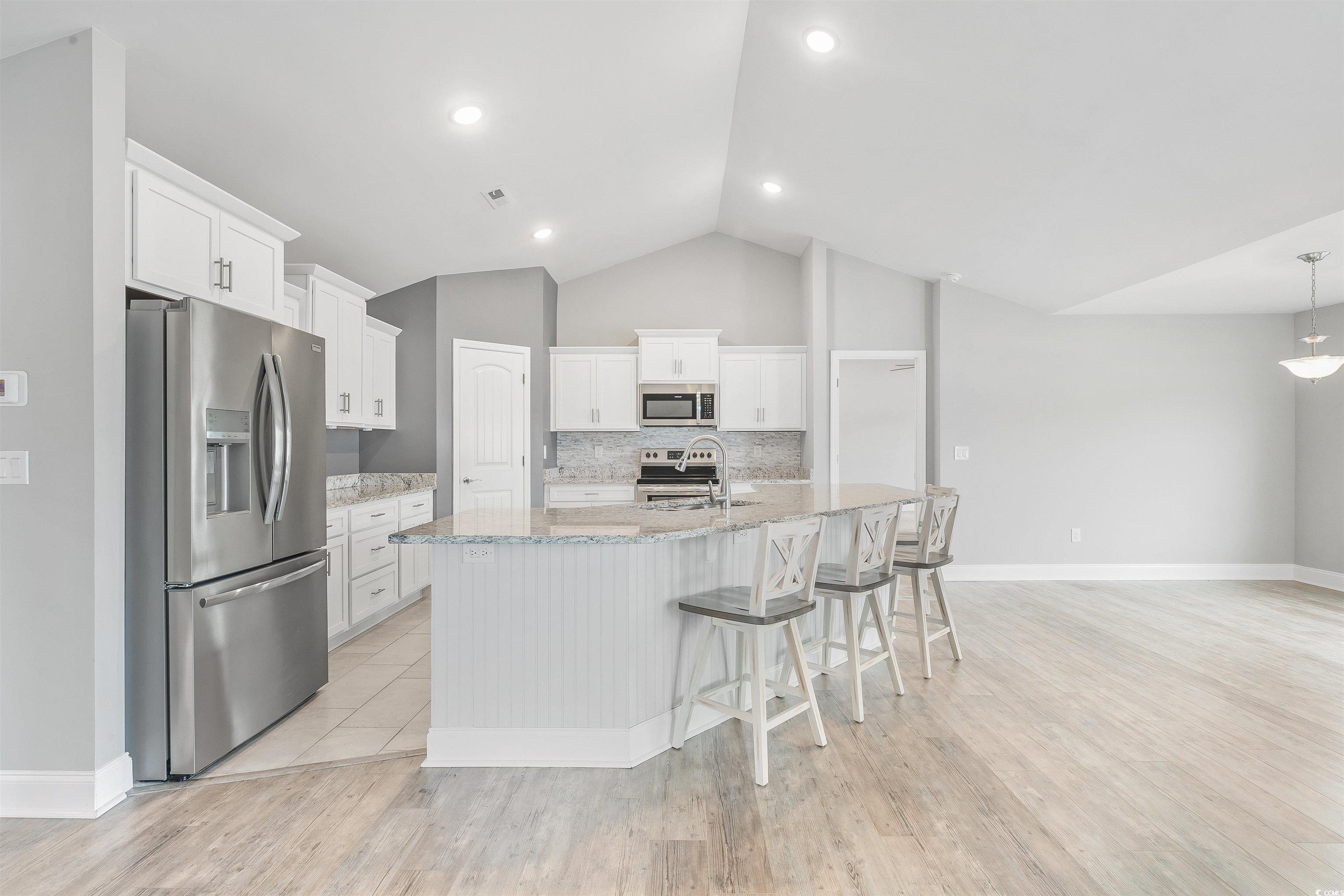 317 Marsh Tacky Loop Myrtle Beach, SC 29588 - Photo 6 of 29 Kitchen featuring lofted ceiling, white cabinets,