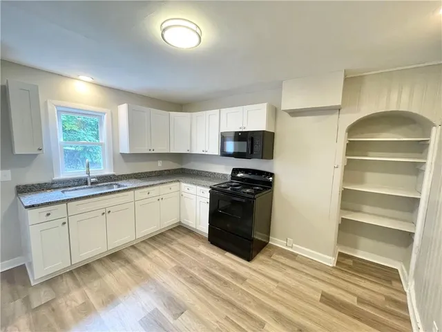 a kitchen with granite countertop a stove a sink and a refrigerator