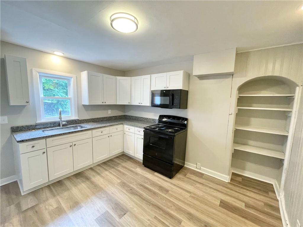 223 East Falls Street, Unit 1B New Castle, PA 16101 - Photo 5 of 14 a kitchen with granite countertop a stove a sink and a refrigerator
