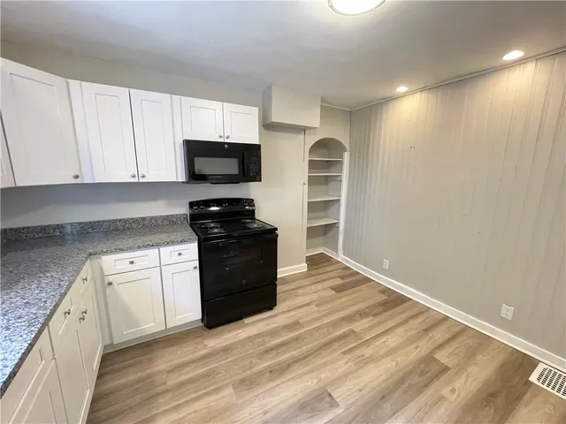 a kitchen with granite countertop a refrigerator and a stove top oven
