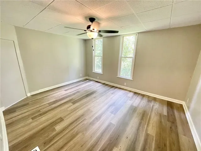 a view of empty room with wooden floor and fan