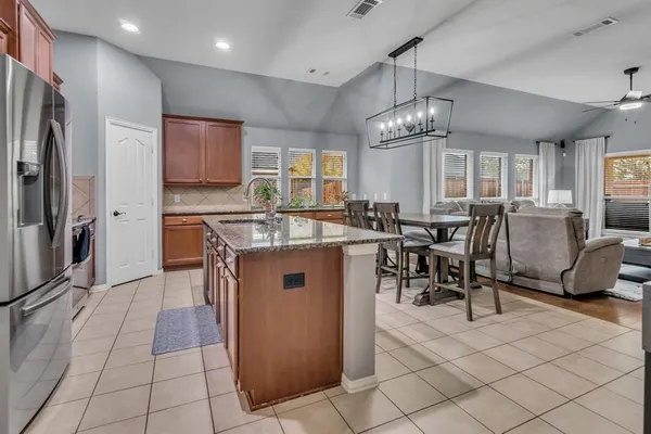 a kitchen with stainless steel appliances granite countertop a sink a stove a refrigerator and a dining table