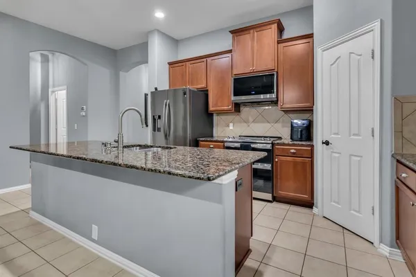 a kitchen with stainless steel appliances granite countertop a refrigerator and a stove top oven
