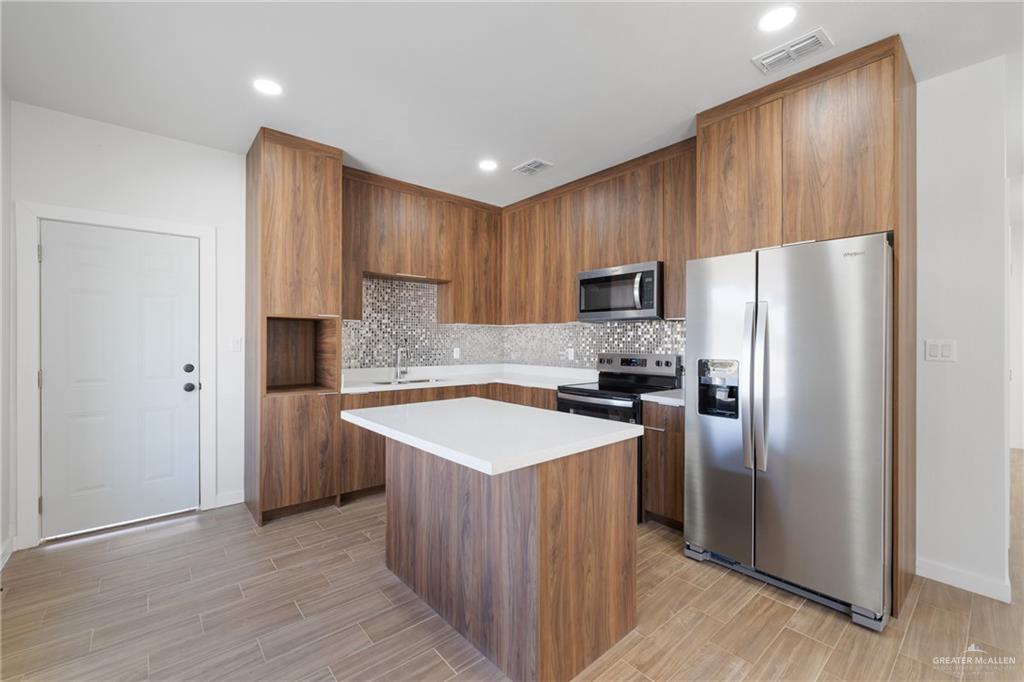 2900 Gabriel Street, Unit 4 Mission, TX 78574 - Photo 2 of 14 a kitchen with kitchen island granite countertop wooden cabinets a refrigerator and a sink