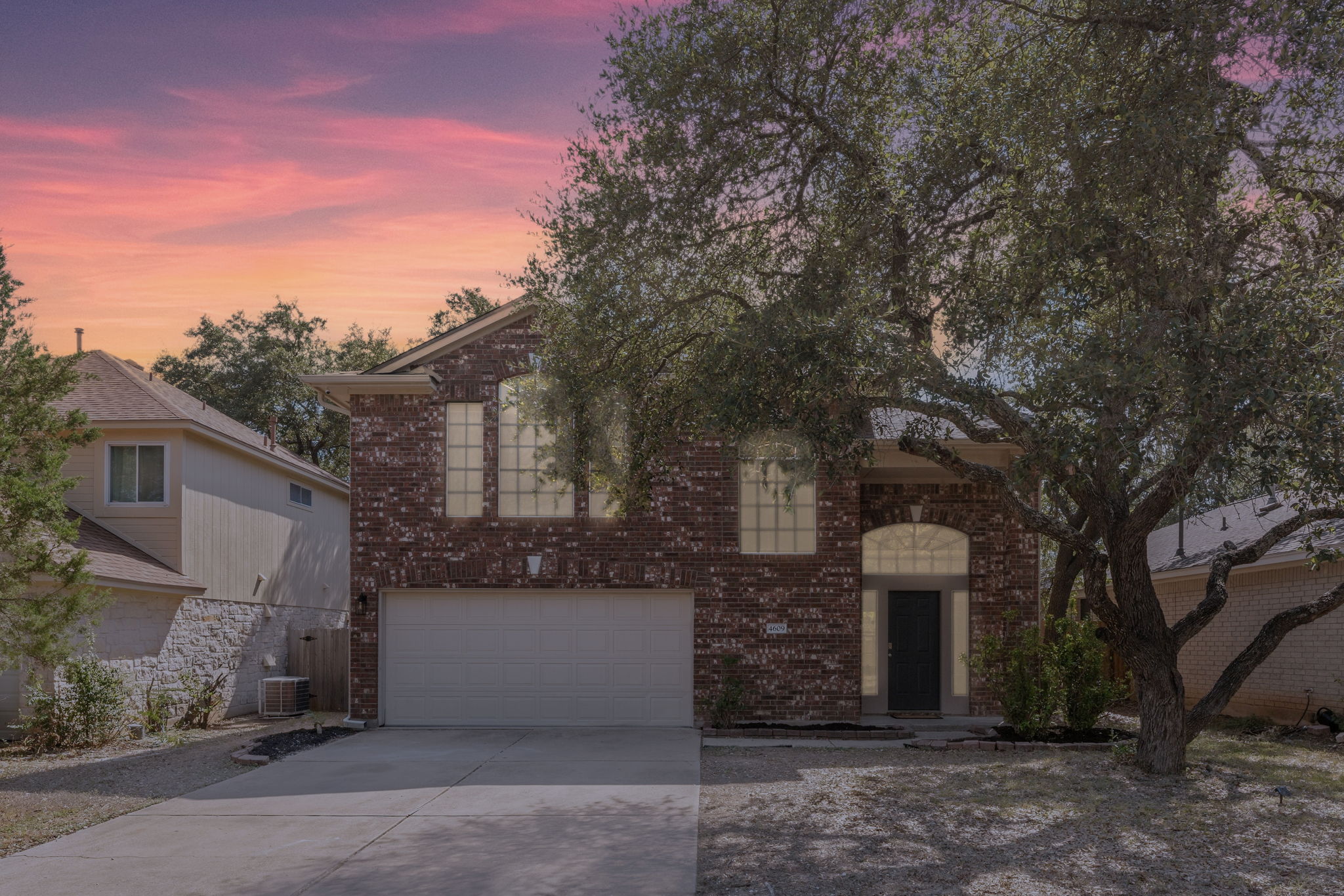 4609 Walsall Loop Austin, TX 78749 - Photo 39 of 39 Stately brick exterior showcasing a two-car garage alongside arched windows and mature shade trees.