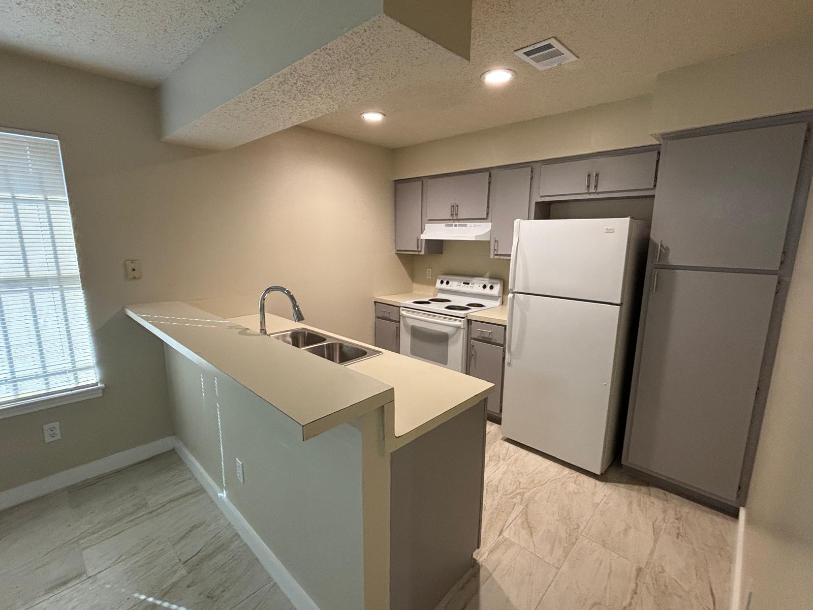 Functional kitchen design showcases a multi-level breakfast bar and modern tile flooring.