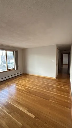 a view of an empty room with window and wooden floor