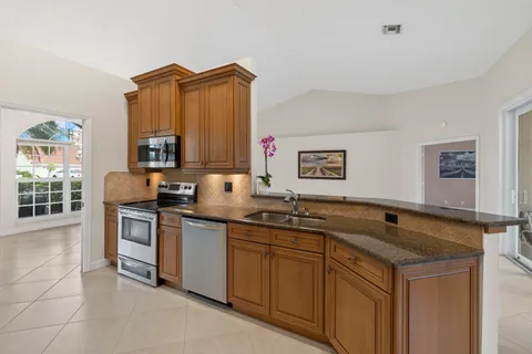 a kitchen with stainless steel appliances granite countertop a refrigerator a sink a stove and chairs