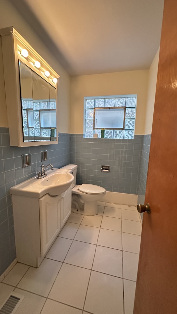 5728 North McVicker Avenue, Unit 1 Chicago, IL 60646 - Photo 5 of 8 a bathroom with a bathtub sink mirror and toilet