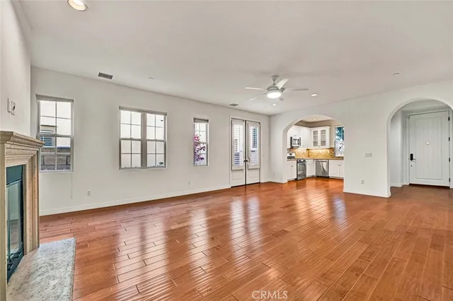 an empty room with wooden floor and a kitchen
