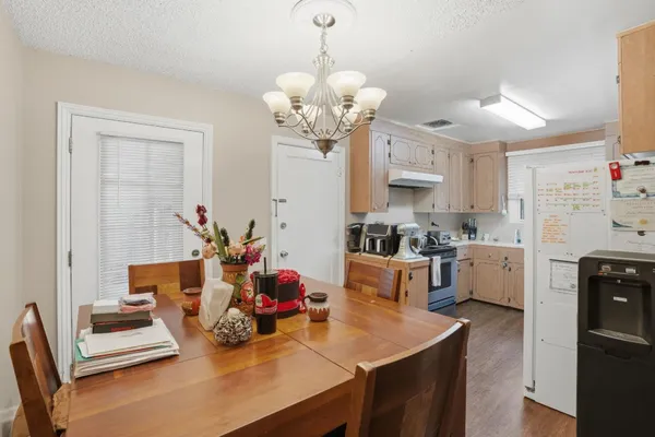 a dining room with kitchen island stainless steel appliances furniture a chandelier and a view of kitchen