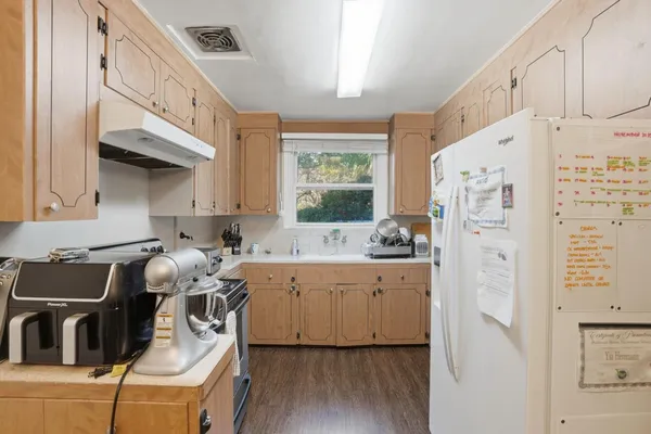 a kitchen with stainless steel appliances a refrigerator a sink a stove and white cabinets