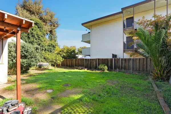 a view of backyard of house with wooden fence