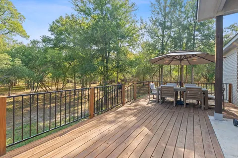 a view of a roof deck with table and chairs under an umbrella with wooden floor and fence