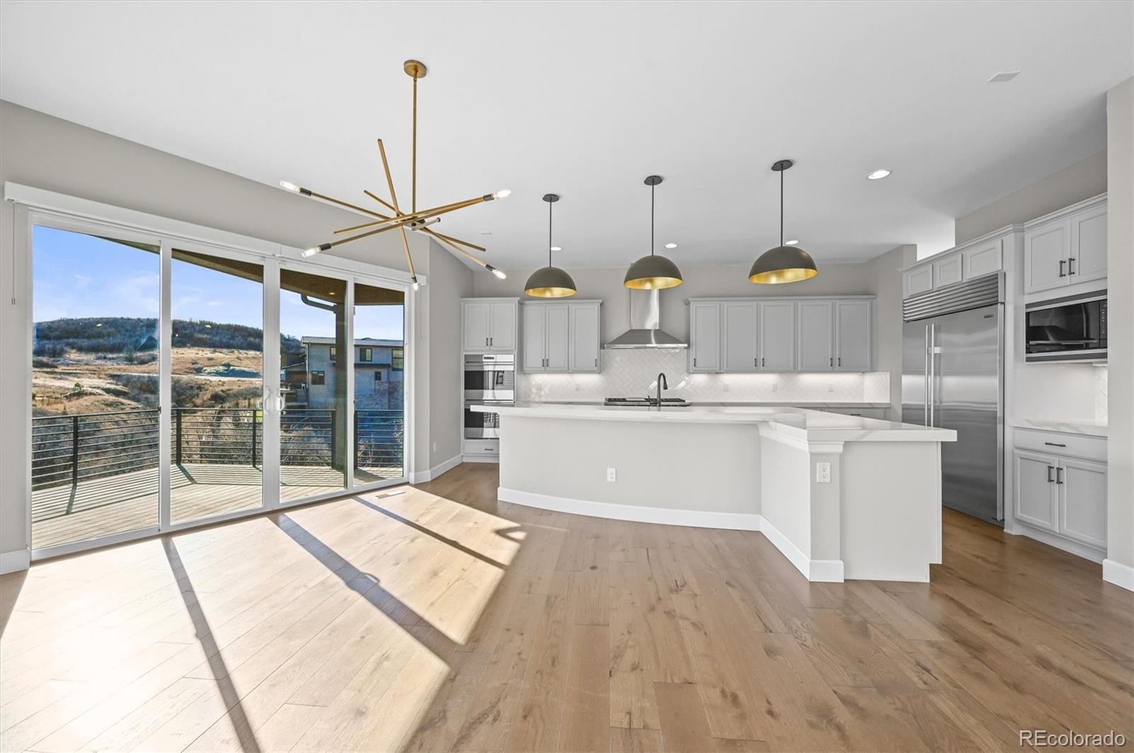 10814 Bluffside Drive Lone Tree, CO 80124 - Photo 4 of 50 a large kitchen with kitchen island a large counter top space a stove and a chandelier