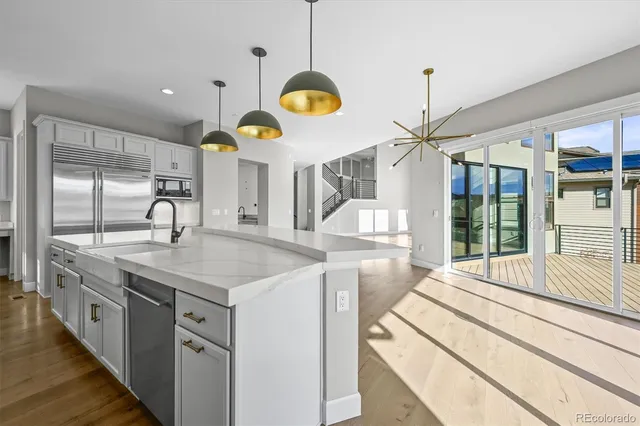 a kitchen with stainless steel appliances granite countertop a sink a stove and a wooden floors