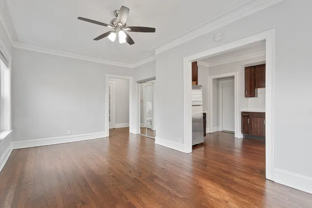 a view of an empty room with a kitchen and wooden floor