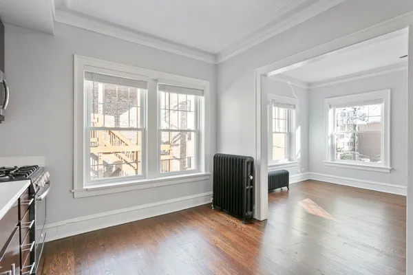 a view of an empty room with a window and wooden floor