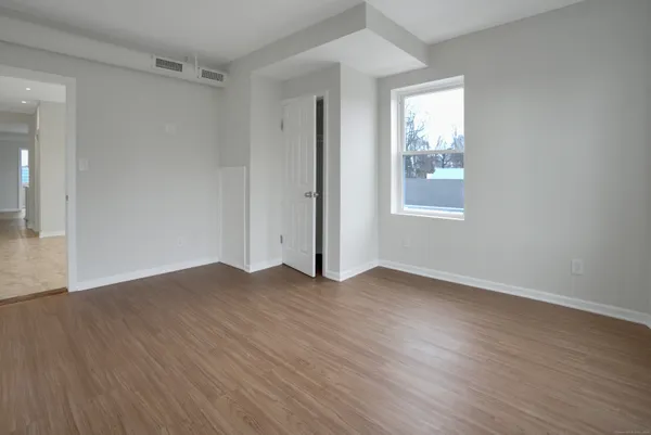 an empty room with wooden floor and windows