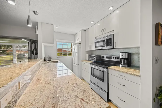 a large kitchen with stainless steel appliances granite countertop a stove a sink and a microwave